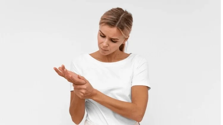 Žena s bolnim zglobom jer ne uzima kurkumin Mlada žena se drži za zglob ruke koji ju boli jer ne uzima dovoljno kurkumina